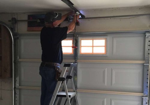 garage door technician installing garage door opener and repair